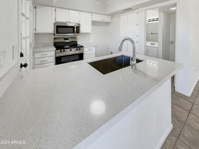 kitchen featuring sink, white cabinets, kitchen peninsula, stainless steel appliances, and light stone countertops