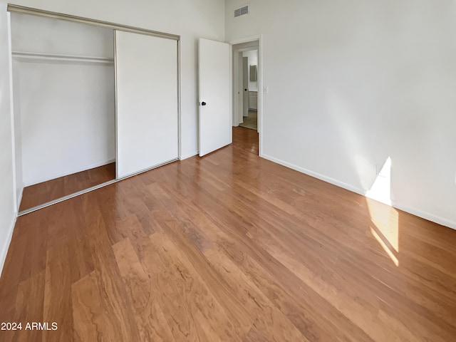 unfurnished bedroom with light wood-type flooring and a closet