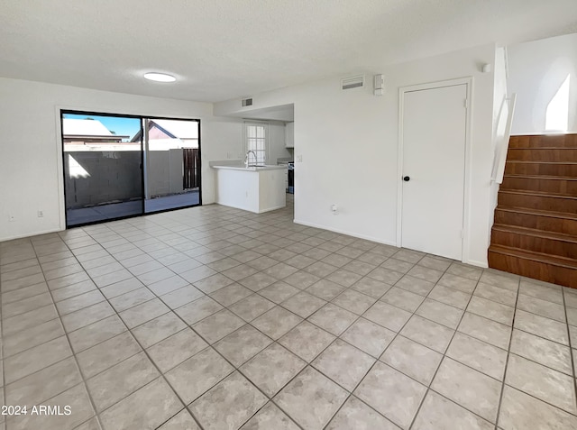 interior space with a textured ceiling, light tile patterned flooring, and sink