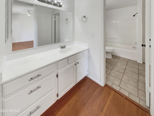 full bathroom featuring shower / bathtub combination, hardwood / wood-style flooring, ceiling fan, vanity, and toilet