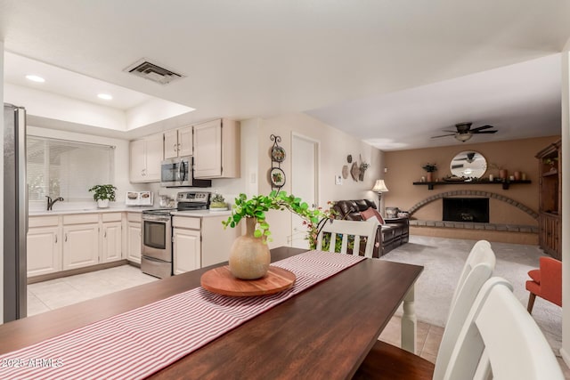 tiled dining area with sink, ceiling fan, and a tray ceiling