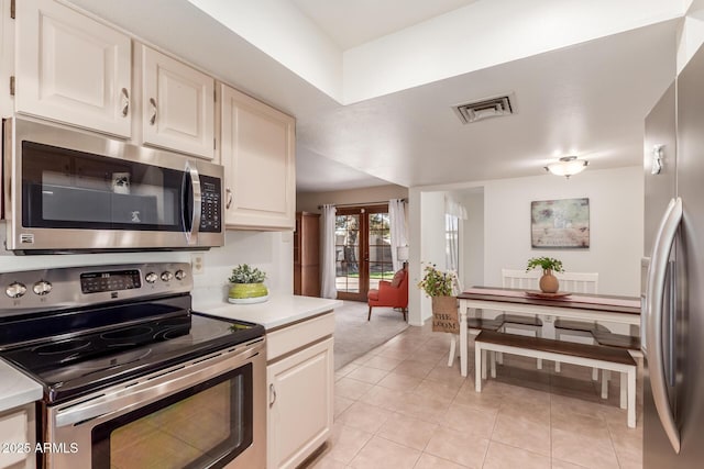 kitchen featuring french doors, white cabinetry, appliances with stainless steel finishes, and light tile patterned flooring