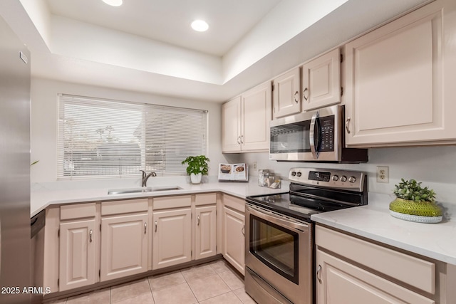 kitchen with sink, a raised ceiling, light tile patterned floors, and appliances with stainless steel finishes