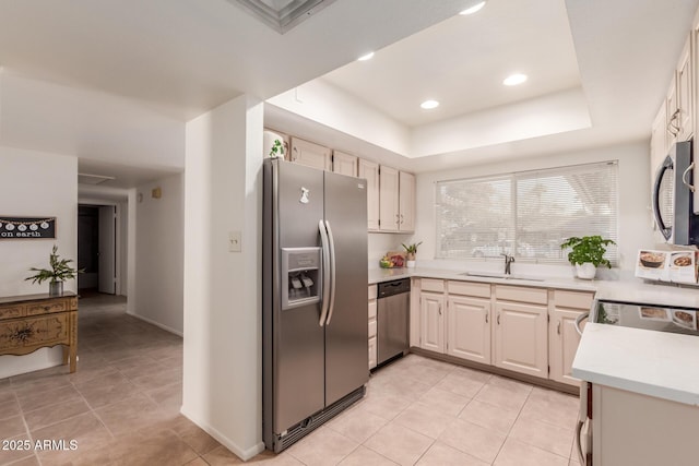 kitchen with light tile patterned floors, sink, appliances with stainless steel finishes, and a raised ceiling