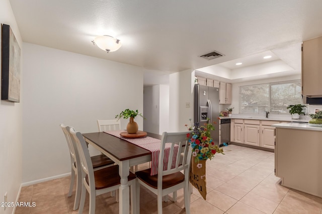 dining room with sink, light tile patterned floors, and a tray ceiling