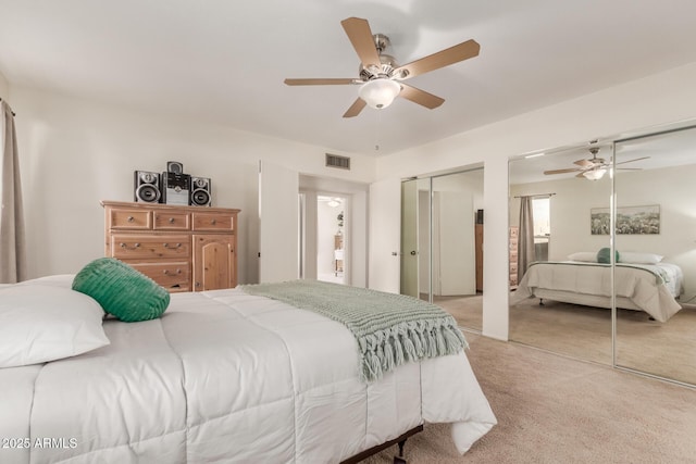 carpeted bedroom featuring ceiling fan and two closets