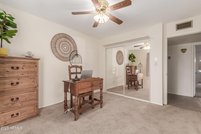 carpeted office space featuring ceiling fan