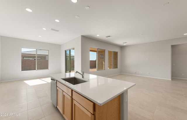 kitchen with stainless steel dishwasher, sink, a kitchen island with sink, and light tile patterned flooring