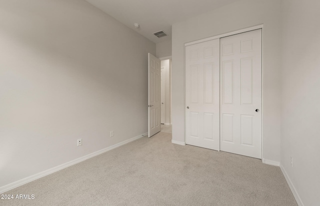 unfurnished bedroom featuring a closet and light colored carpet