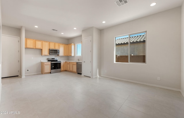 kitchen with light brown cabinets, stainless steel appliances, and light tile patterned floors