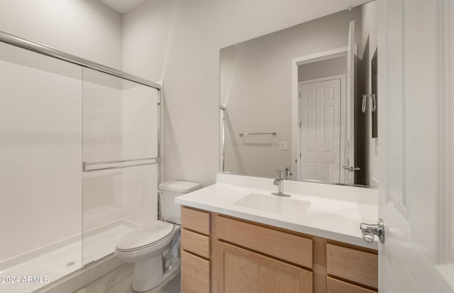 bathroom featuring vanity, a shower with shower door, and toilet