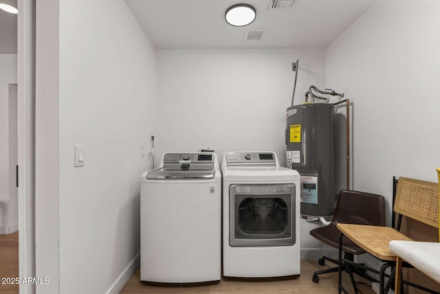 washroom featuring separate washer and dryer, electric water heater, and light wood-type flooring