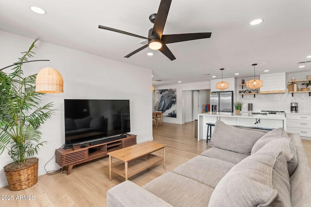 living room featuring ceiling fan and light hardwood / wood-style floors