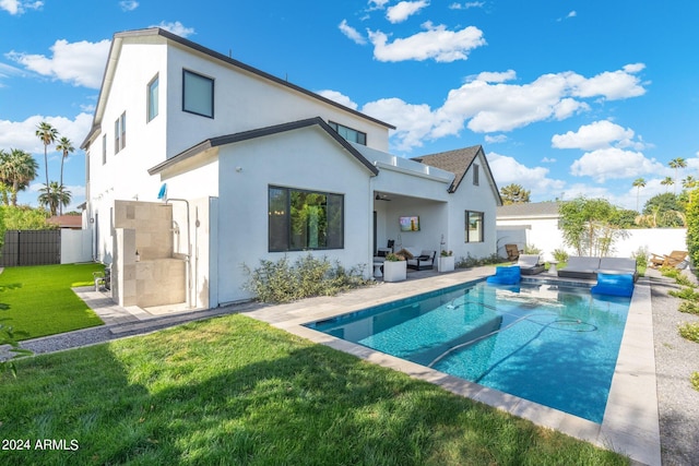 back of house featuring a lawn, a fenced in pool, outdoor lounge area, and a patio