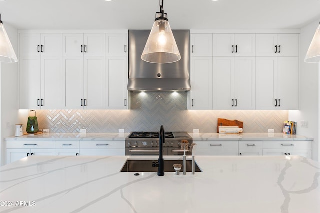 kitchen featuring pendant lighting, backsplash, high end stainless steel range, and wall chimney exhaust hood