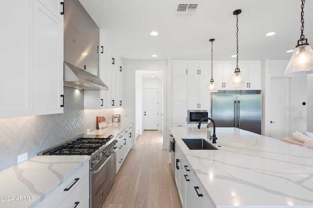 kitchen with built in appliances, decorative light fixtures, white cabinetry, and sink