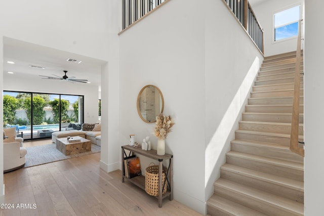 stairway featuring hardwood / wood-style floors, a towering ceiling, and ceiling fan