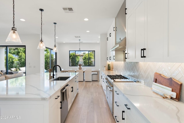 kitchen with white cabinets, decorative light fixtures, sink, and stainless steel appliances