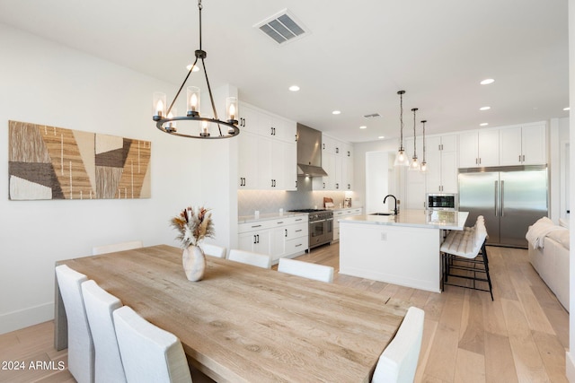 dining area featuring light hardwood / wood-style floors, sink, and a chandelier