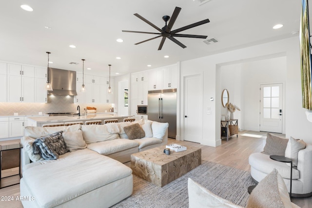 living room featuring ceiling fan, sink, and light wood-type flooring