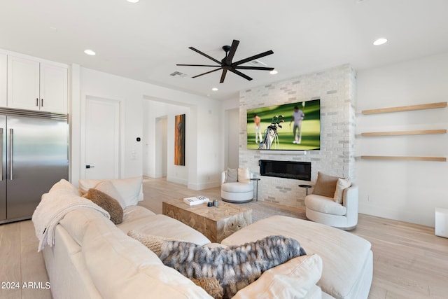 living room with light wood-type flooring, a brick fireplace, and ceiling fan