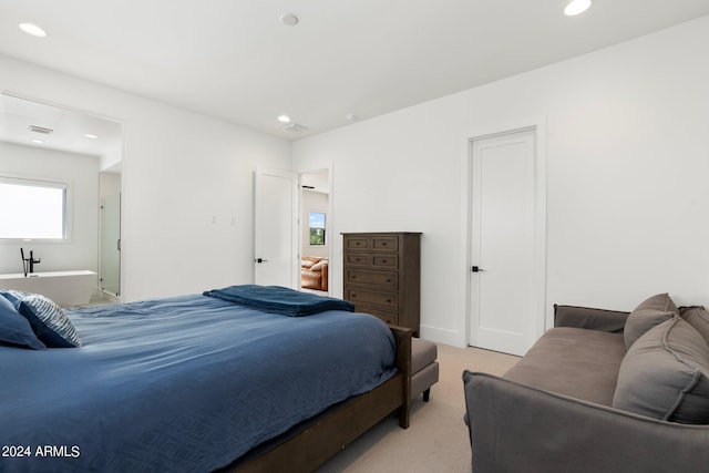 bedroom featuring ensuite bathroom and light carpet