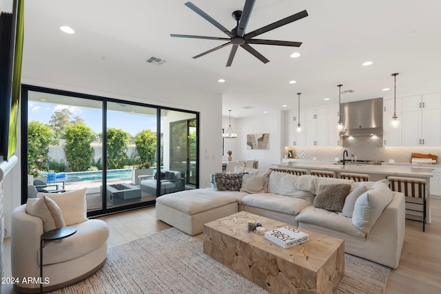 living room featuring ceiling fan, light hardwood / wood-style floors, sink, and a wealth of natural light