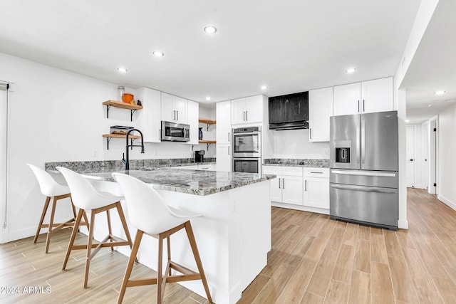 kitchen with white cabinetry, a breakfast bar area, dark stone counters, kitchen peninsula, and stainless steel appliances