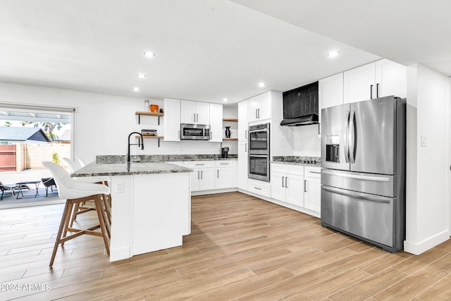 kitchen with white cabinetry, sink, a breakfast bar area, dark stone counters, and stainless steel appliances