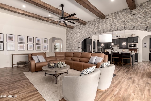 3990 E Iris Dr, Chandler, AZ 85286 - living room with arched walkways, a ceiling fan, light wood-style flooring, beamed ceiling, and baseboards