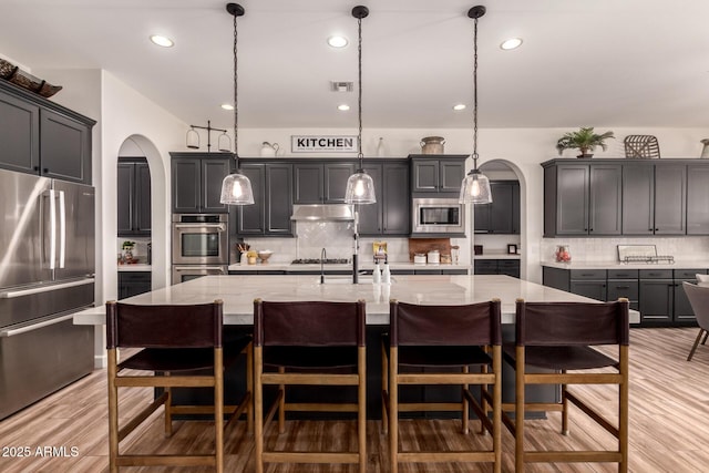 3990 E Iris Dr, Chandler, AZ 85286 - kitchen featuring appliances with stainless steel finishes, arched walkways, decorative backsplash, light stone countertops, and recessed lighting