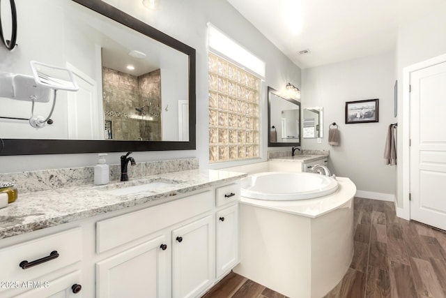 full bathroom featuring a sink, a garden tub, wood finished floors, and a shower stall