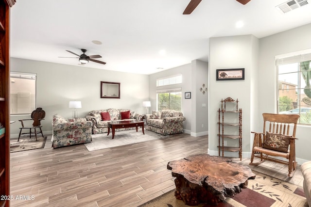 living area with a wealth of natural light, visible vents, and ceiling fan