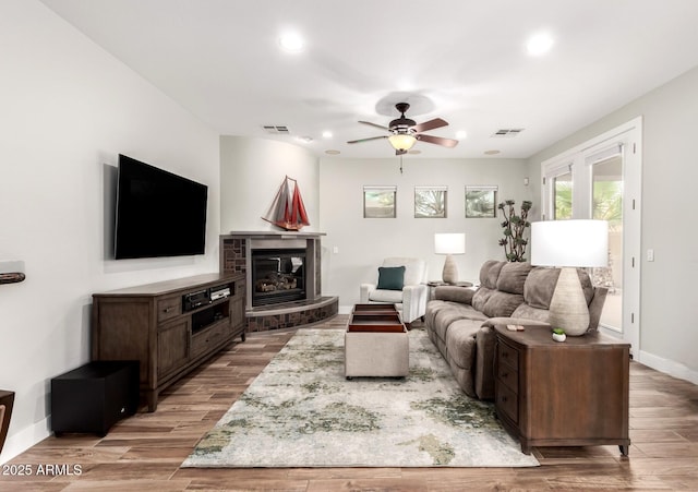 living area featuring visible vents, baseboards, ceiling fan, and wood finished floors