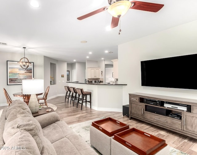 living room featuring a ceiling fan, visible vents, baseboards, light wood-style flooring, and recessed lighting