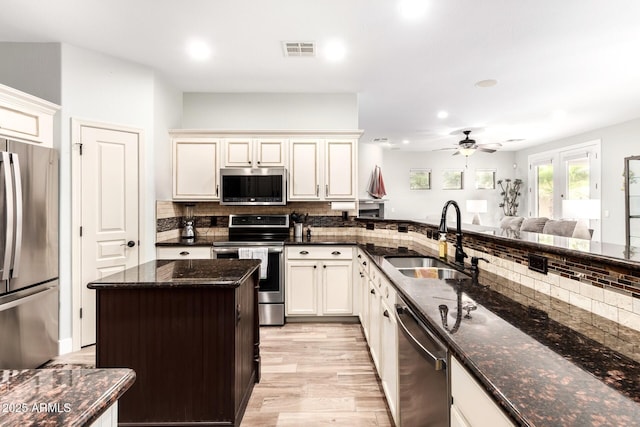 kitchen with visible vents, dark stone counters, decorative backsplash, stainless steel appliances, and a sink