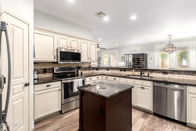 kitchen with visible vents, light wood finished floors, a sink, decorative backsplash, and appliances with stainless steel finishes