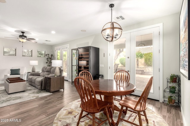 dining area with visible vents, ceiling fan with notable chandelier, and light wood-type flooring