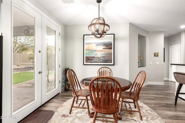 dining space featuring french doors, baseboards, an inviting chandelier, and wood finished floors