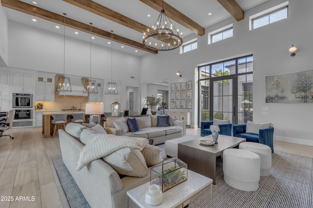 living area with baseboards, beamed ceiling, a towering ceiling, and a notable chandelier