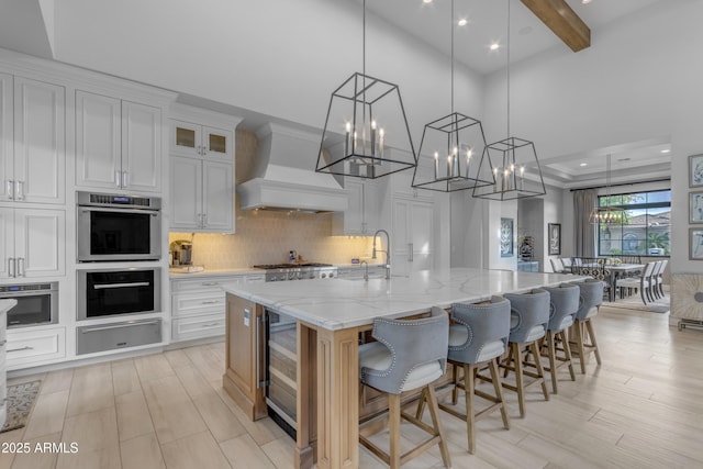 kitchen with stainless steel appliances, a spacious island, custom exhaust hood, a warming drawer, and tasteful backsplash