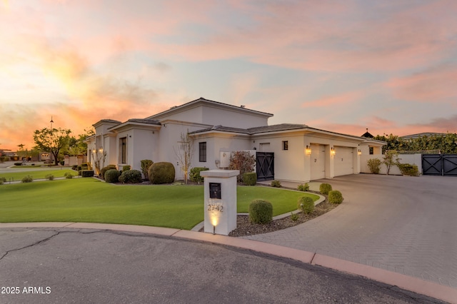 mediterranean / spanish house featuring a garage, a yard, decorative driveway, and stucco siding