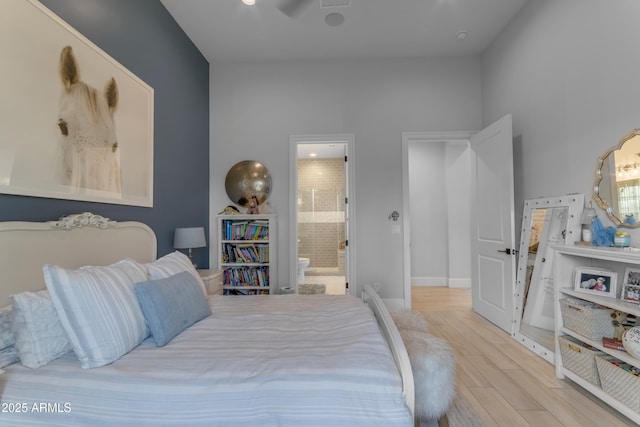 bedroom featuring connected bathroom, baseboards, and wood finished floors