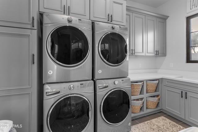 washroom featuring cabinet space, independent washer and dryer, stacked washing maching and dryer, and tile patterned floors