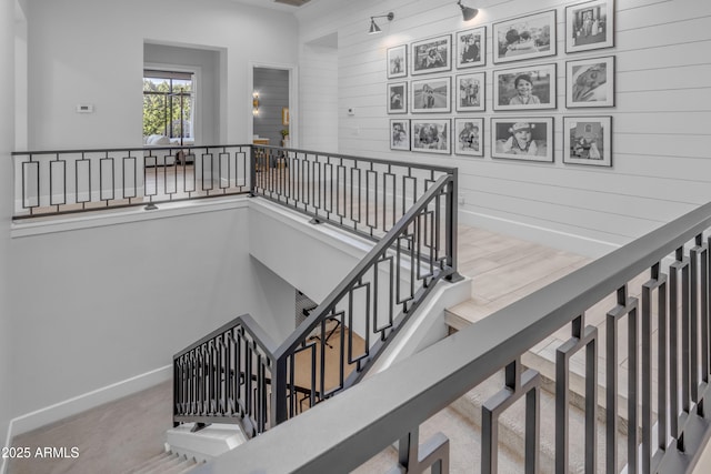 staircase featuring carpet, wooden walls, and baseboards