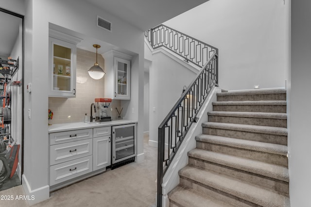 stairs featuring carpet floors, wine cooler, indoor wet bar, visible vents, and baseboards