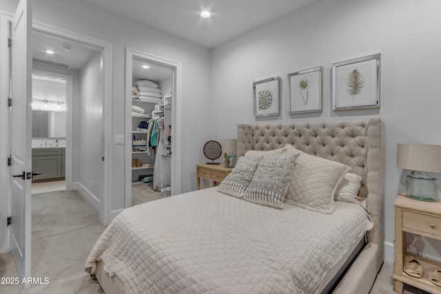 bedroom featuring recessed lighting, light colored carpet, a sink, a closet, and a walk in closet