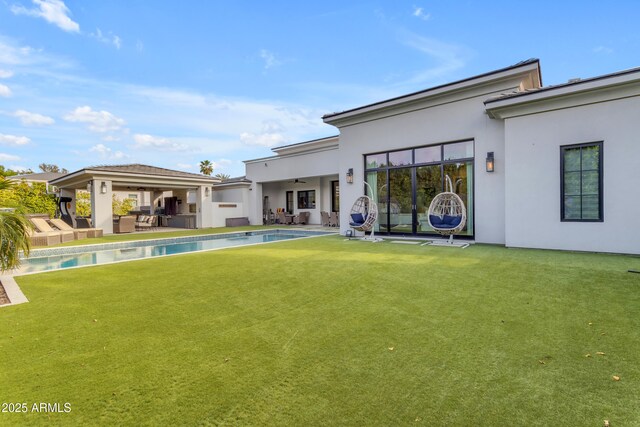 back of property featuring ceiling fan, a patio, area for grilling, a lawn, and stucco siding