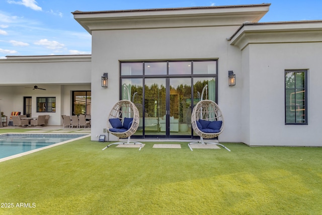 back of property featuring an outdoor pool, a patio area, a yard, and stucco siding