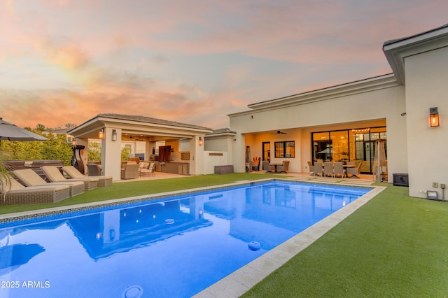 outdoor pool with an outdoor hangout area, a patio, and a yard